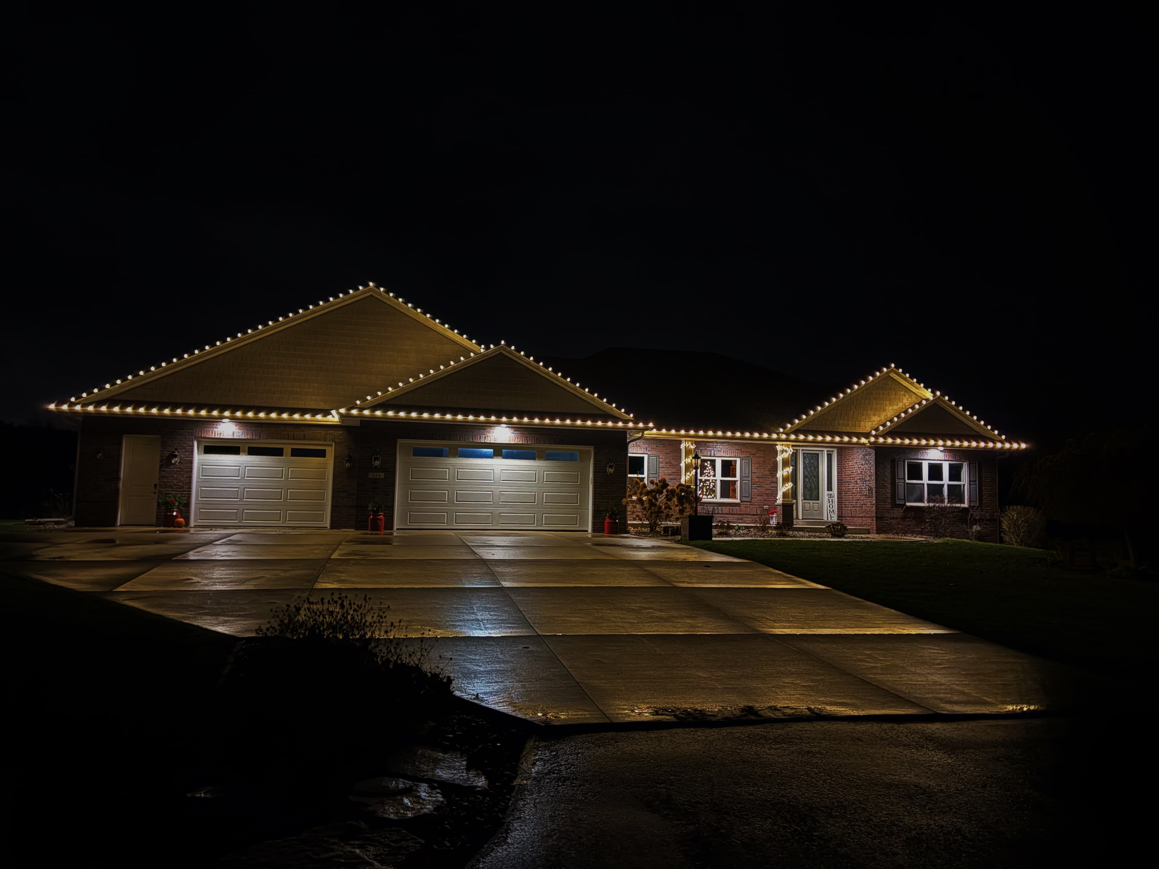 Kussmaul Co. holiday lighting installation on single-story brick home at night