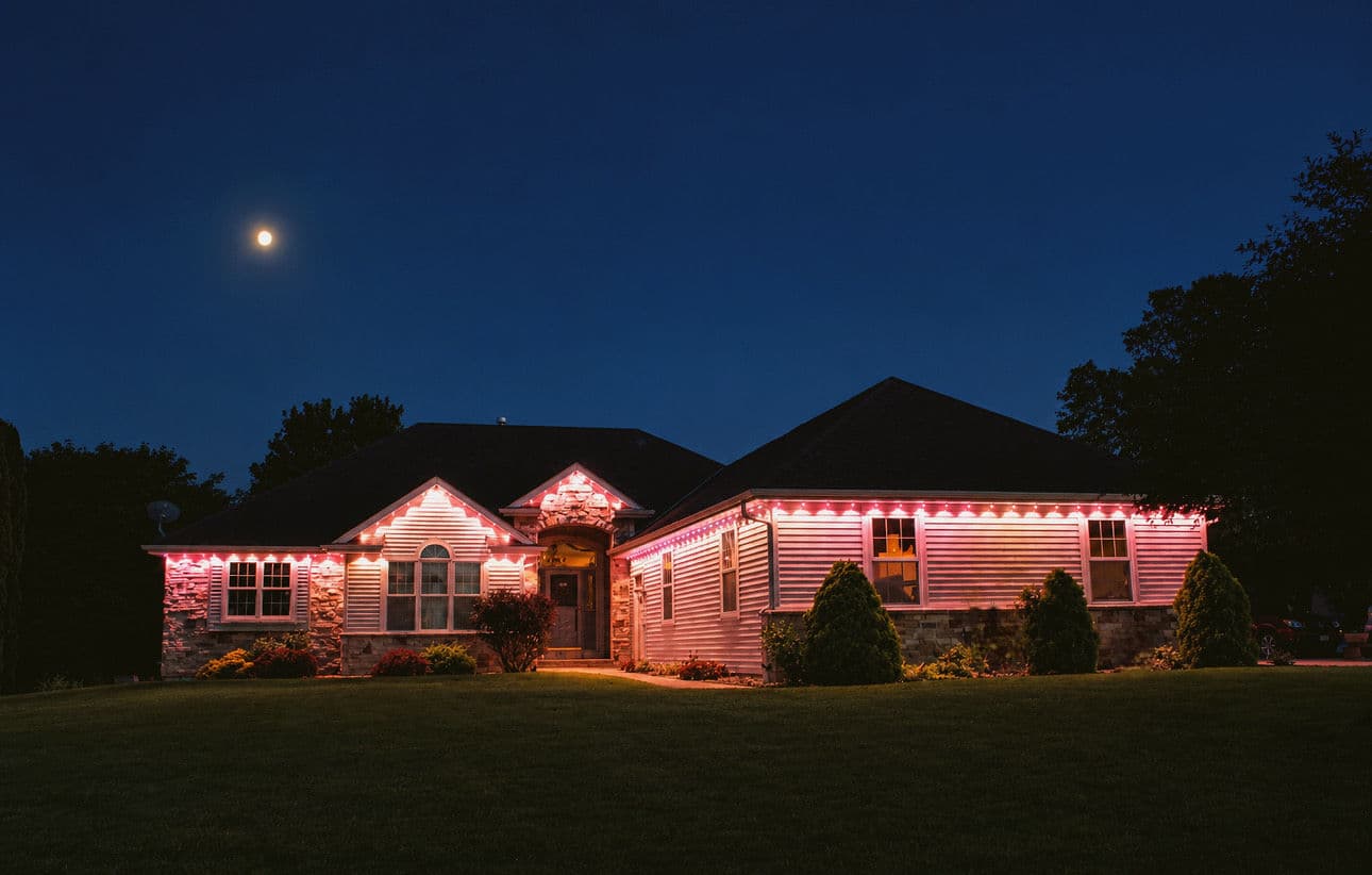 Kussmaul Co. holiday lighting: warm white roofline with lit porch pillars at night