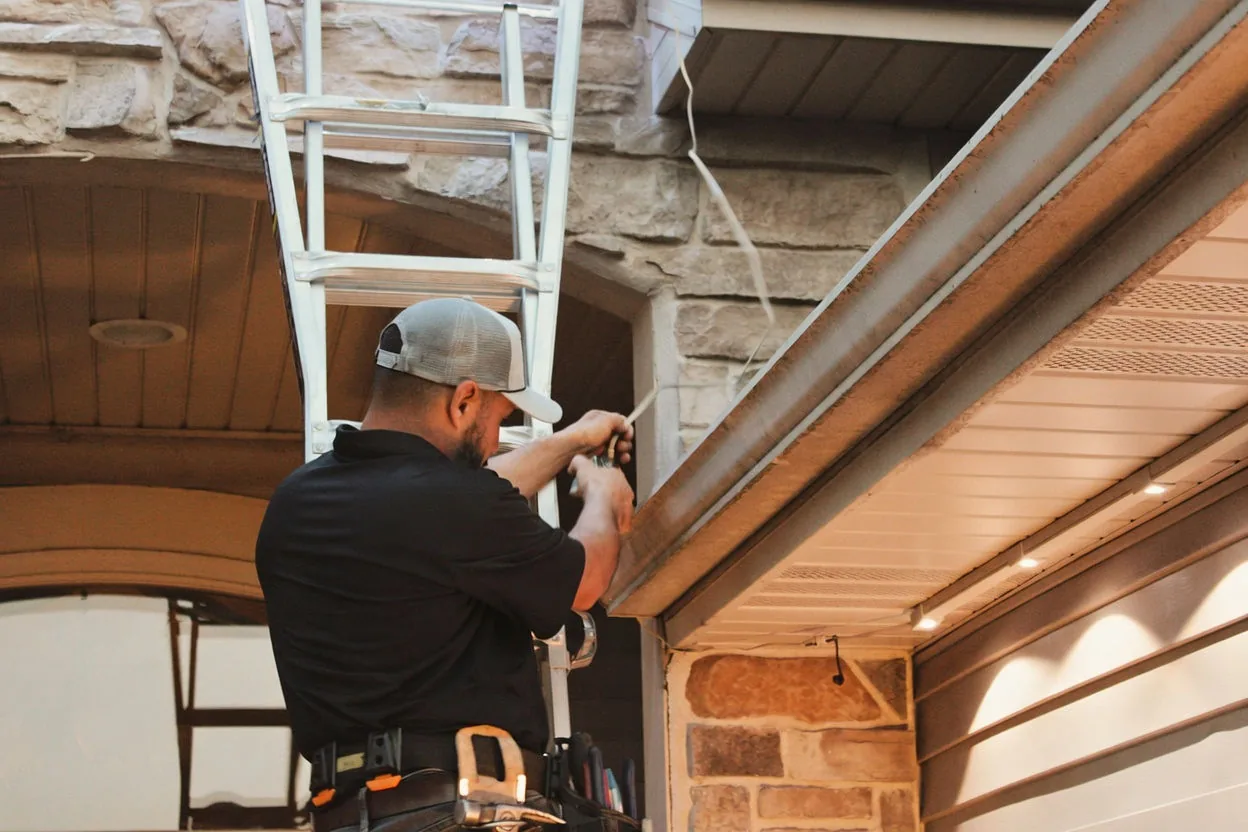 Kussmaul Co. installer on a ladder fastening lighting track above a stone entry