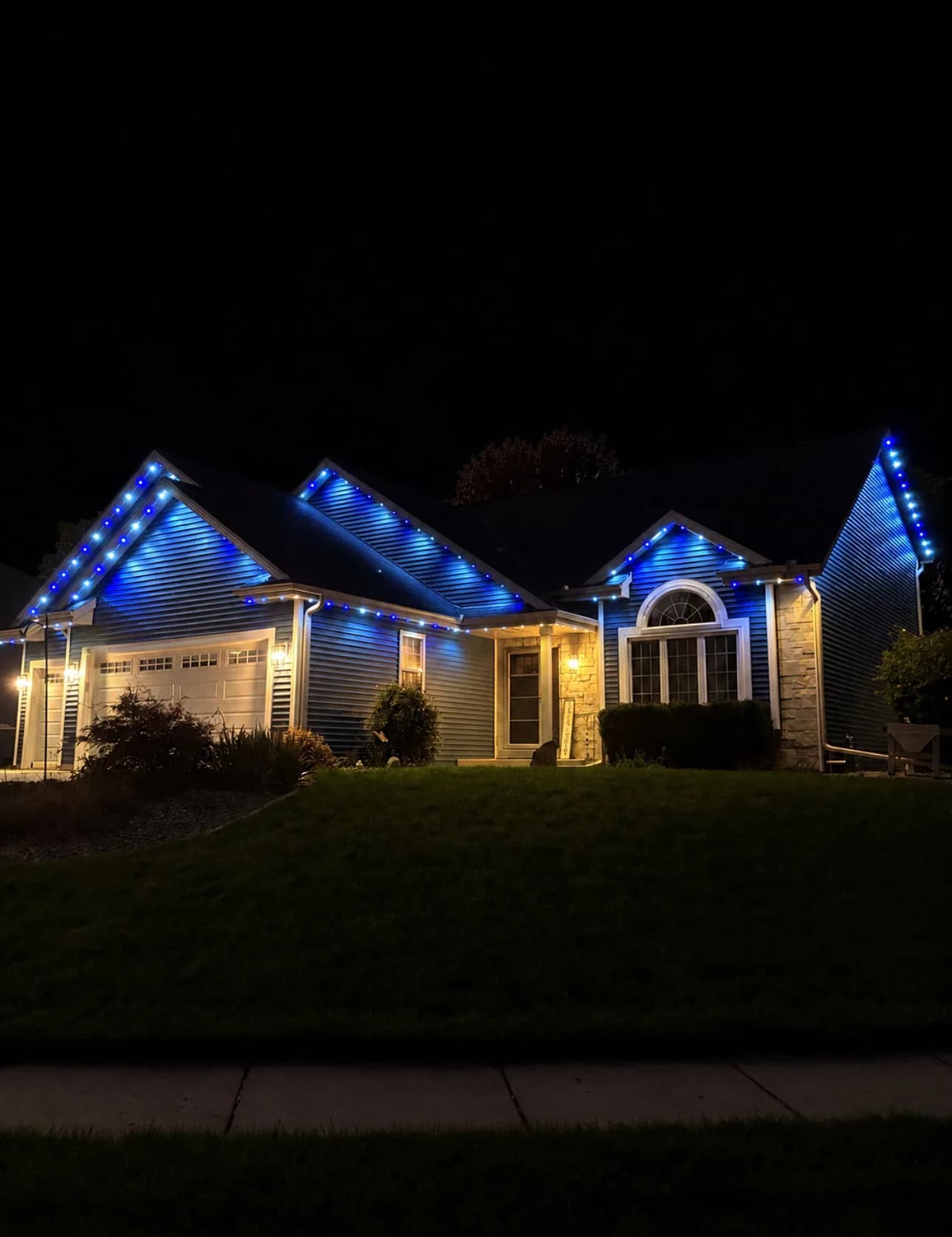 Real Kussmaul Co. permanent lighting in blue along every gable and eave of a ranch home at night