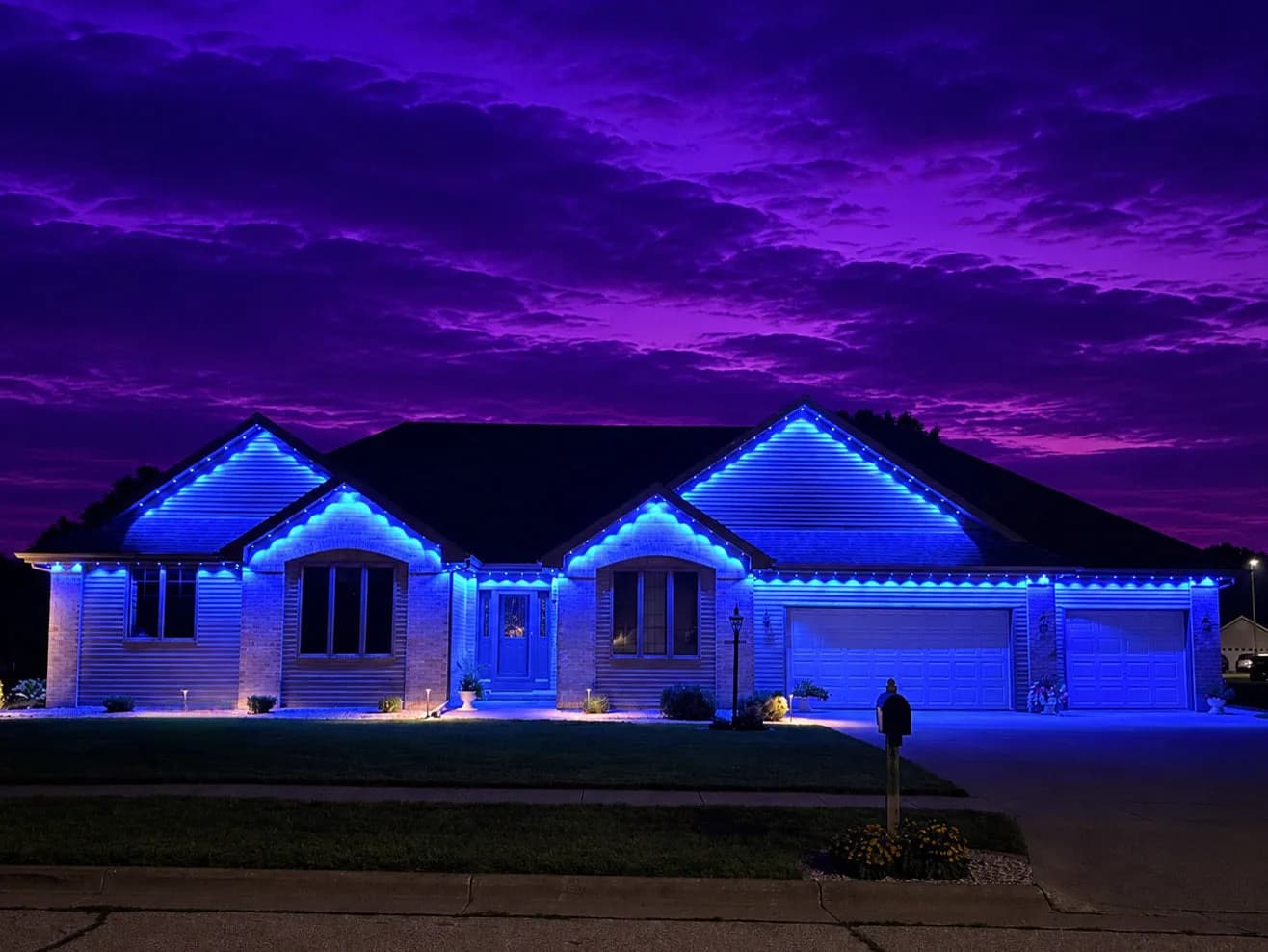 Real Kussmaul Co. permanent lighting in blue across a full roofline under a vivid purple sunset