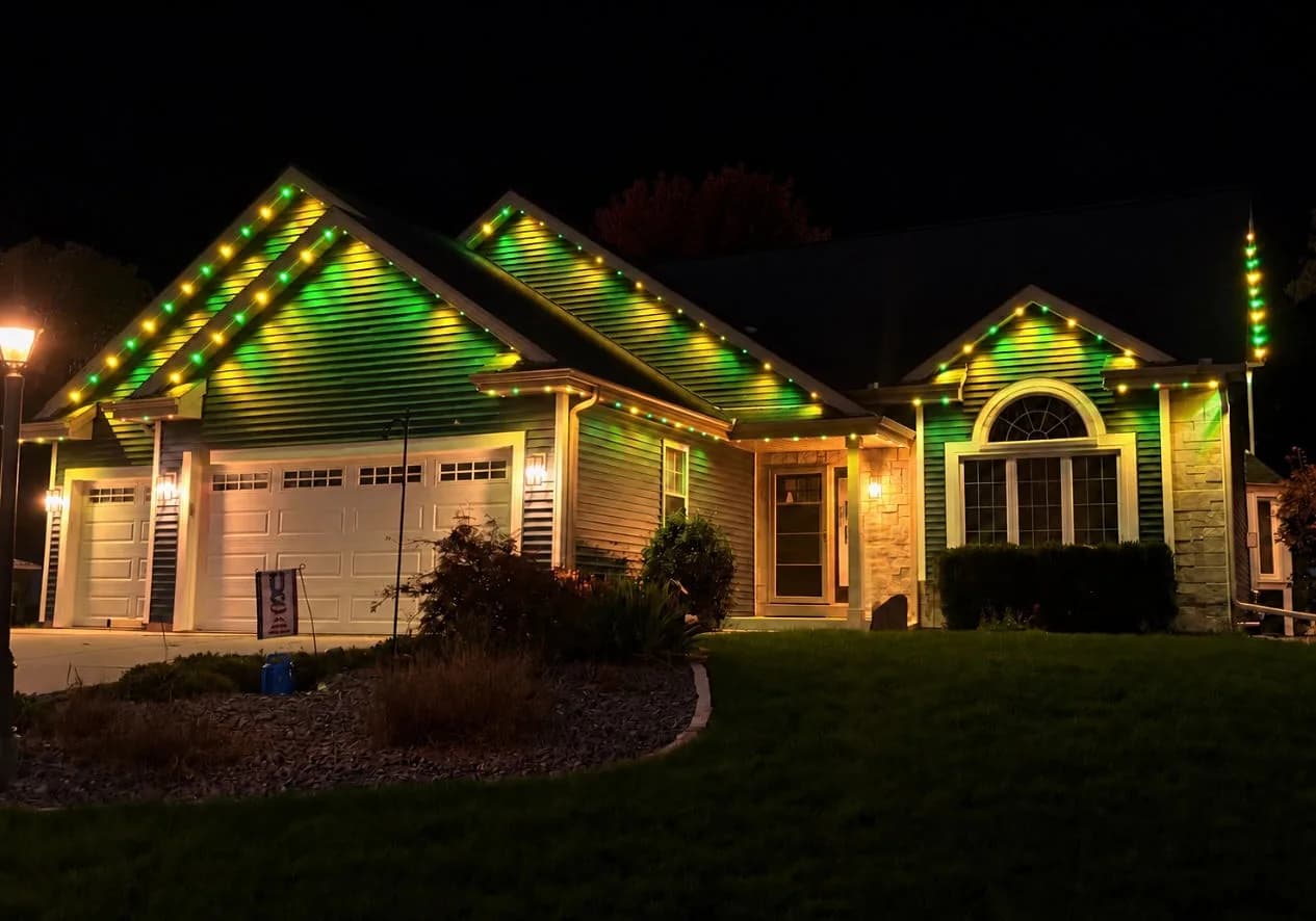 Real Kussmaul Co. permanent lighting in green and gold game-day colors along a ranch home's gables