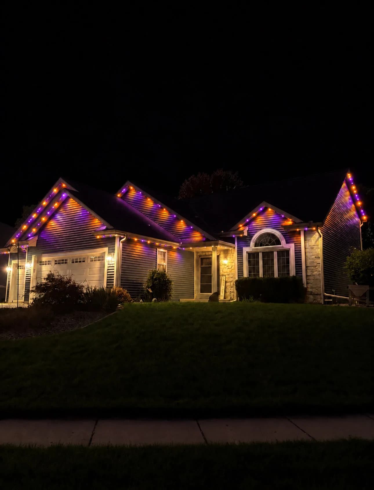 Real Kussmaul Co. permanent lighting in purple and orange for Halloween along a ranch home's gables