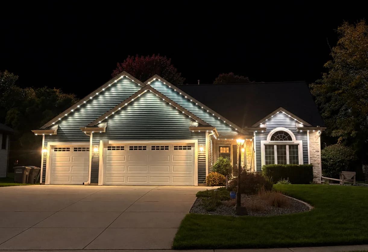 Real Kussmaul Co. permanent lighting in white tracing every gable of a ranch home with a three-car garage