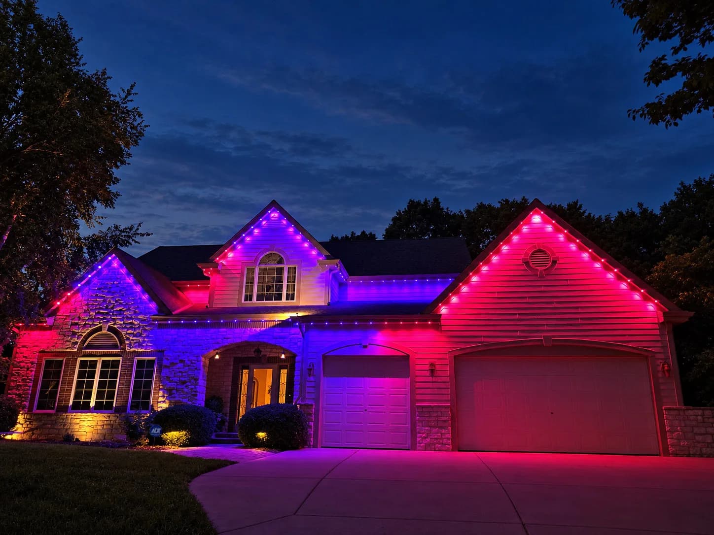 Real Kussmaul Co. permanent lighting in red and blue across a stone two-story home's gables