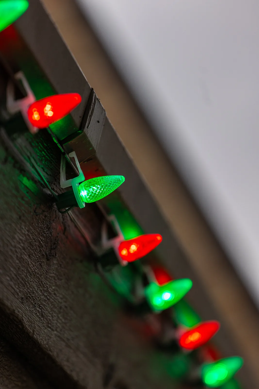 Macro detail of red and green C9 bulbs along a gutter line for a real Kussmaul Co. holiday lighting install