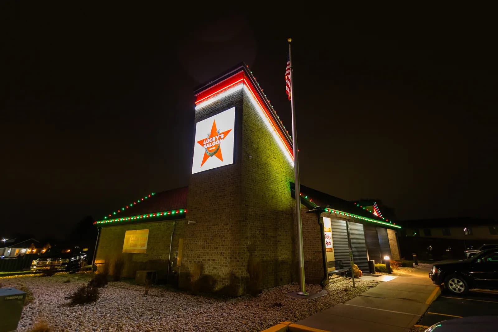 Real Kussmaul Co. holiday lighting installation on a brick commercial building, red and green roofline lights at night