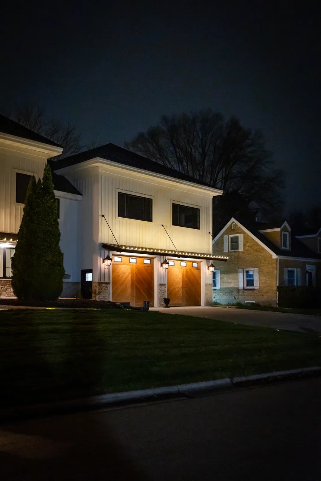 Real Kussmaul Co. holiday lighting installation along a large home's garage wing at night