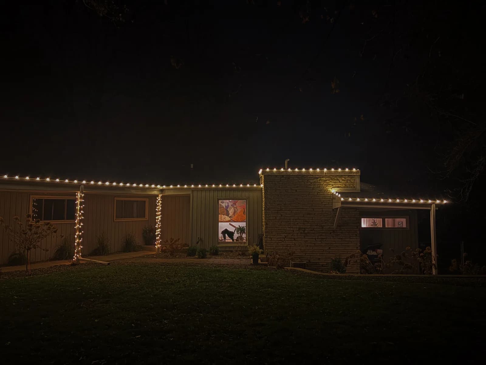 Warm white eave lighting along ranch home roofline at dusk