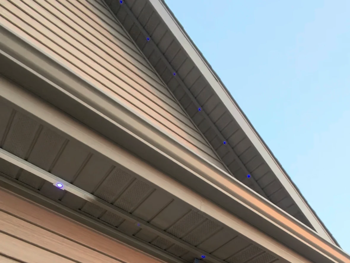 A roofline in daylight with lighting set into color-matched track — no cord, no clips, only the fixtures themselves are faintly visible