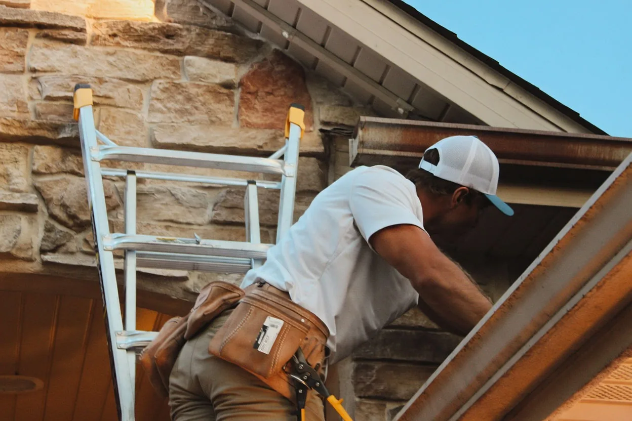 Kussmaul Co. crew member working a gable install from a ladder with a full tool belt