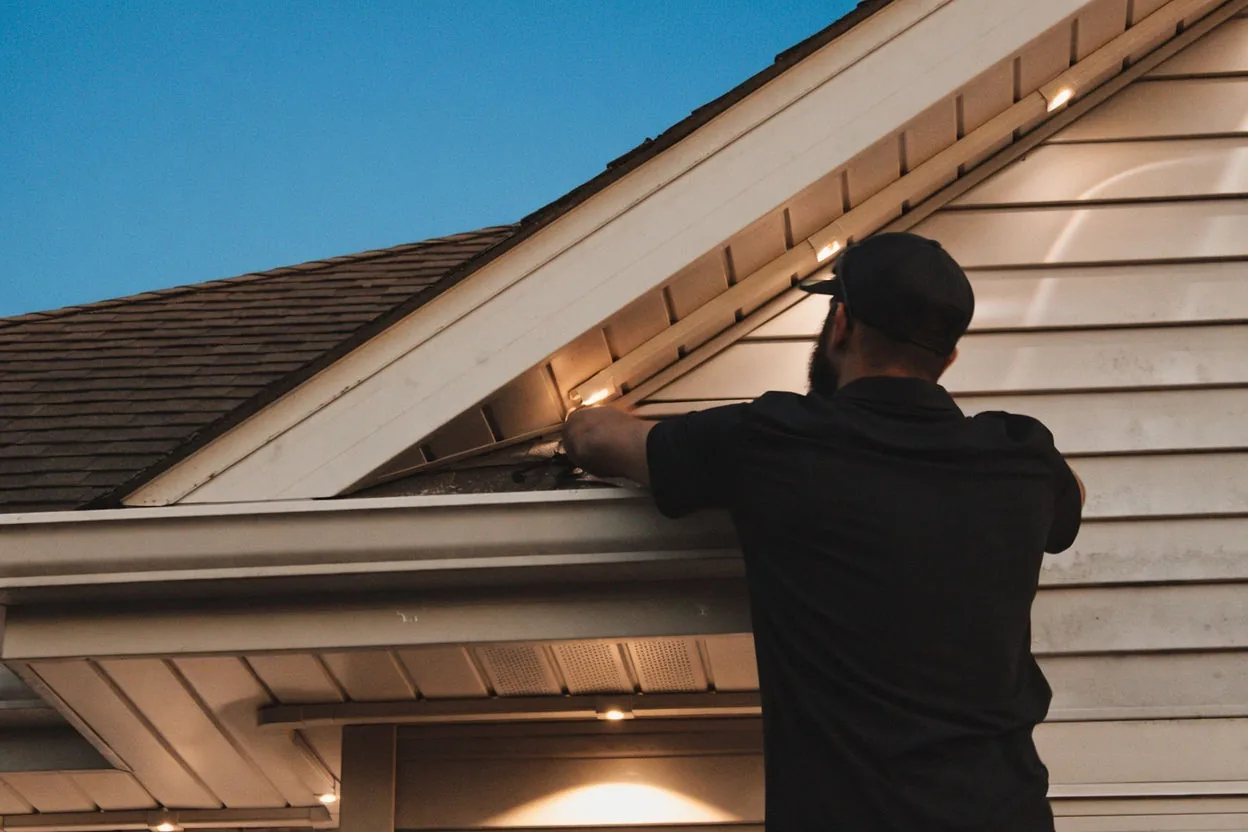 Close view of a Kussmaul Co. installer seating LEDs into the hidden color-matched roofline track at dusk