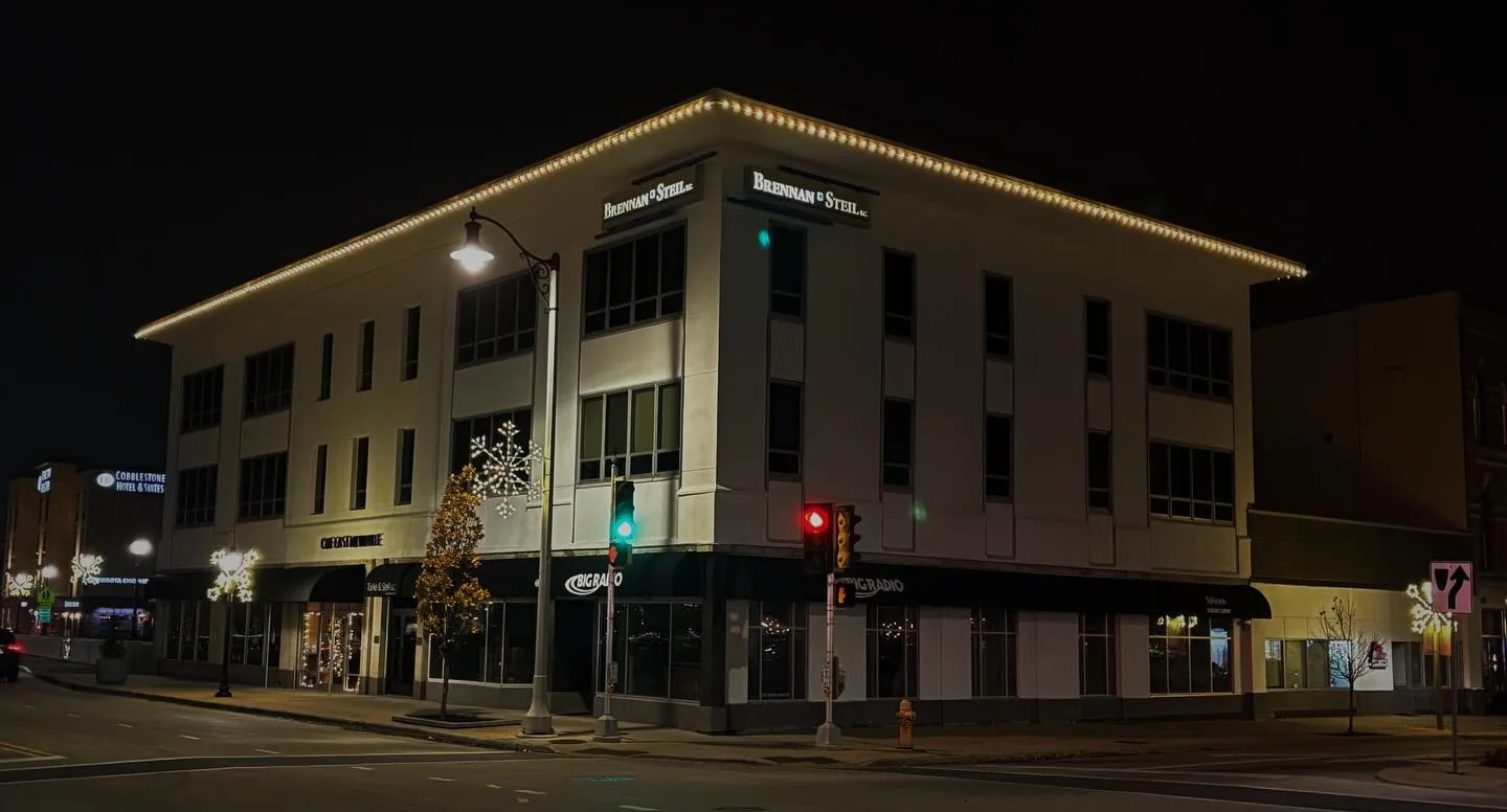 A three-story downtown commercial office building with crisp warm-white holiday roofline lighting installed by Kussmaul Co. — residential and commercial jobs both welcome
