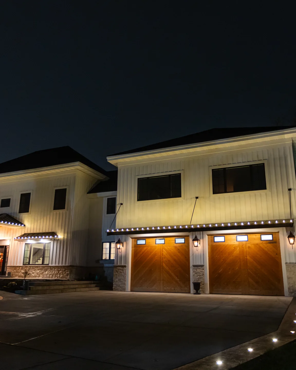 Real Kussmaul Co. holiday lighting installation glowing warmly on a home's garage doors at night