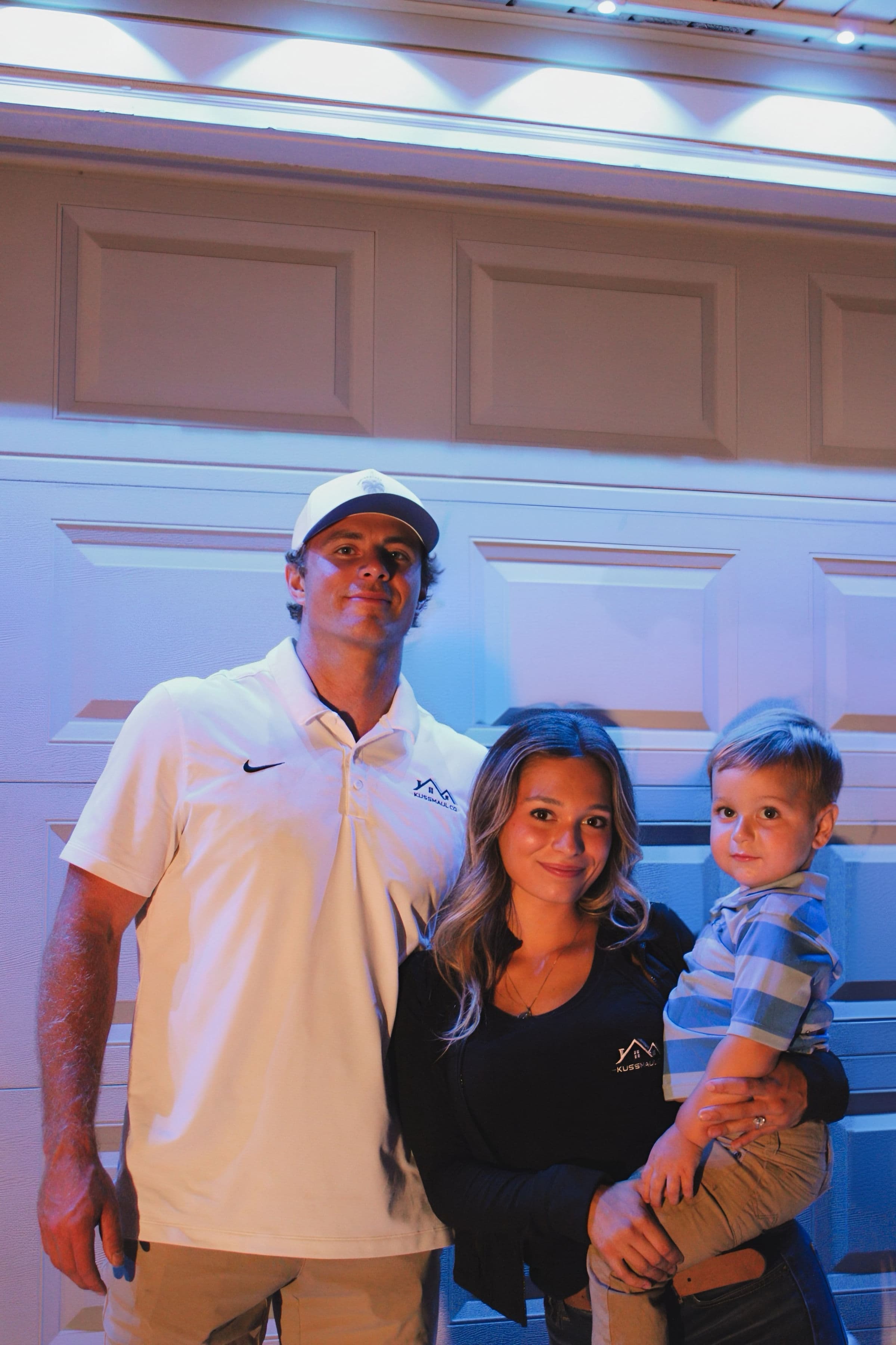Tressin Kussmaul with his fiancée and their son, standing together under a permanent lighting install